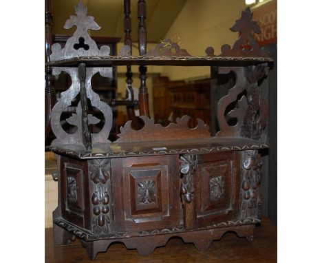 An early 20th century carved oak two-tier wall shelf having twin lower cupboard doors