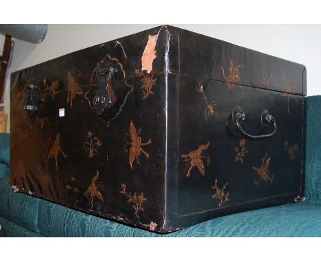 An Eastern black lacquered hinge top travelling trunk, having iron end carry handles, width 90cm