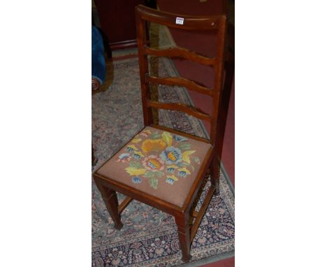 A set of three Edwardian mahogany dining chairs each having a ladder back above an embroidered drop in seat on square tapered