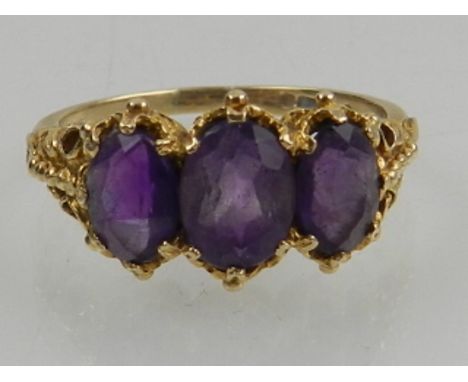 A 9 carat yellow gold and amethyst ring, the ornate mount set with three oval cut amethysts. 