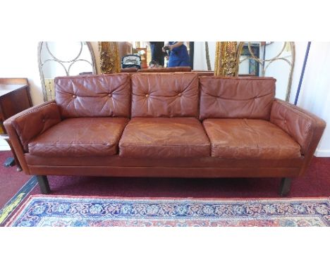 A 20th Century Danish tan leather three seater sofa raised on block legs