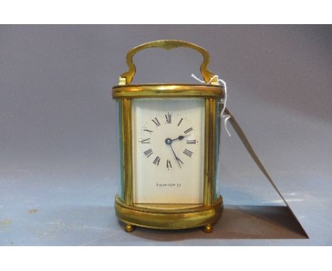 A 20th Century Mappin and Webb brass carriage clock of oval form having bevelled glass panels, raised on bun feet (missing ba