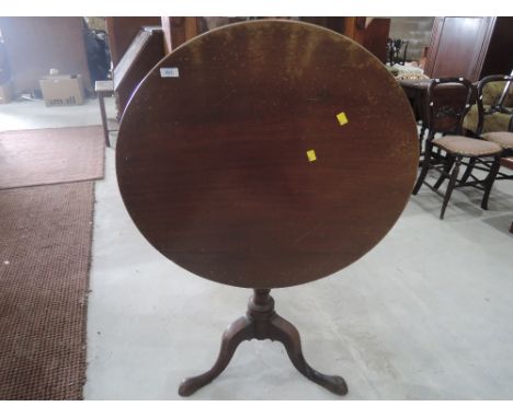 An early 19th century mahogany pedestal table having circular flip top on tripod legs