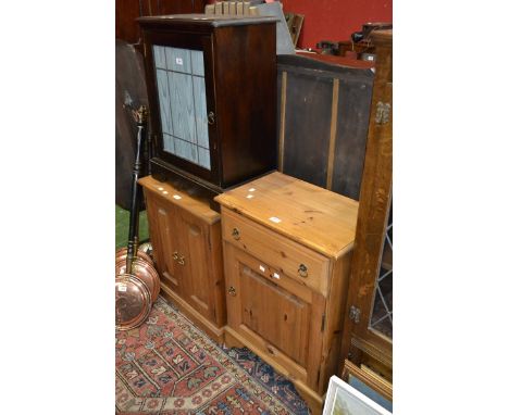 A stained pine side cabinet with glazed door; a pine side cabinet with two door; a pine cabinet, single drawer over fielded p