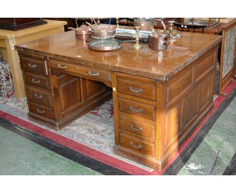 An oak partners desk, oversailing top, kneehole flanked by an arrangement of eight drawers, similar to verso, fielded panels 
