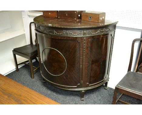 A Regency style demi-lune cabinet, dot and dash beaded top, urns, swags and bows carved in relief to frieze, single crossband