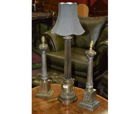 A large brass table lamp, fluted column, the base with scenes of a medieval harbour in relief; two others (3)