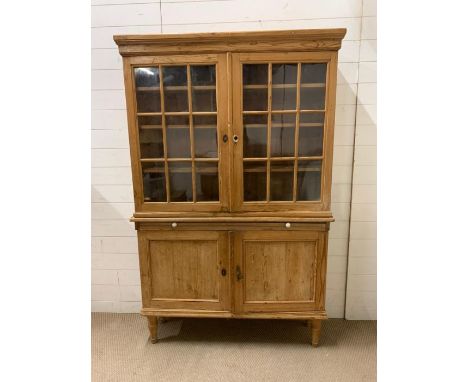 An antique pine kitchen larder with glazed panelled doors and shelf under 