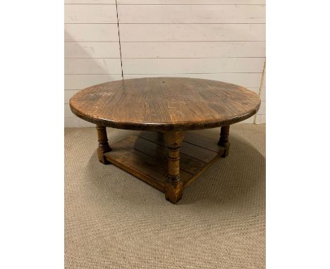 An oak circular low centre table on turned legs and shelf under (H46cm Dia106cm)