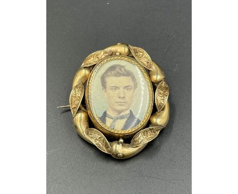 A Pinchbeck rotating brooch with portrait of a gentleman to one side and hair to the other.