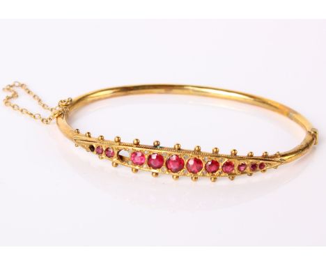 A 9ct gold bangle set with ruby coloured stones (two stones missing), 5.6g in total. 