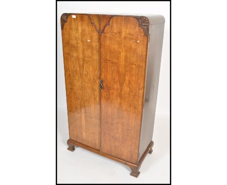 A 1930's Art Deco walnut bachelors wardrobe being raised on shaped leg plinth base with double doors enclosing storage set wi