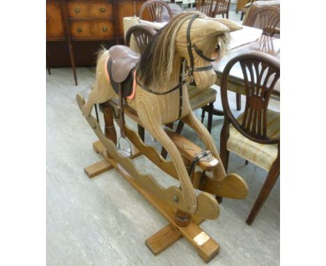A modern carved laminated wood rocking horse with mane, tail and stitched hide saddle, on a crossover base  bears plaque 'Ian