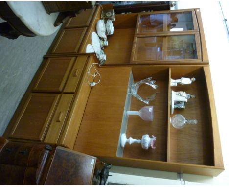 A 1970s teak two section wall unit, having two shelves, over a fall front with a pair of short drawers and twin panelled door