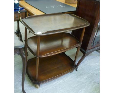 An Ercol stained beech and elm three tier serving trolley, united by turned, tapered pillars, raised on casters  30''h  29''w