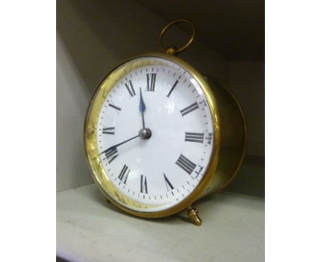 An early 20thC lacquered brass drum cased timepiece with a ring handle; the movement faced by a white enamel Roman dial  4''d