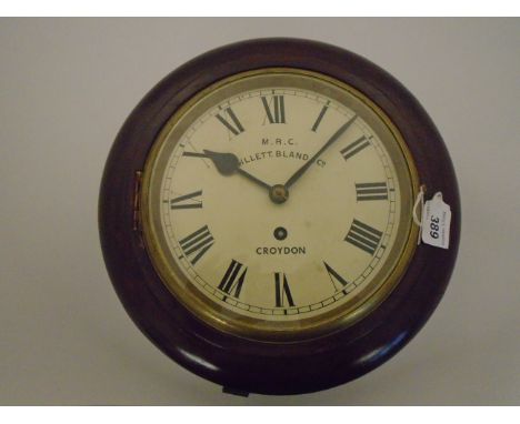 A ROUND WALL HANGING SCHOOL CLOCK BY MRC GILLETT BLAND AND CO WITH ROUND ENAMELLED DIAL AND ROMAN NUMERALS 