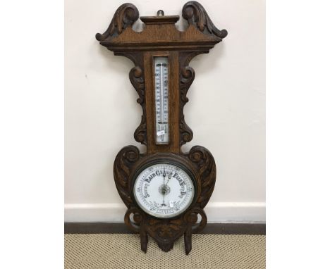 A circa 1900 carved oak cased aneroid barometer thermometer 85 cm high x 34 cm wide