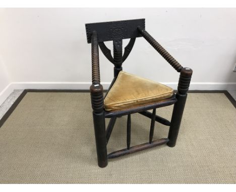 An oak corner chair in the 17th Century manner, the carved bar back over bobbin turned arms and panel seat within turned side