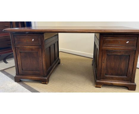 A modern oak double pedestal desk, the top with moulded edge above a central drawer flanked by short drawers and cupboard doo