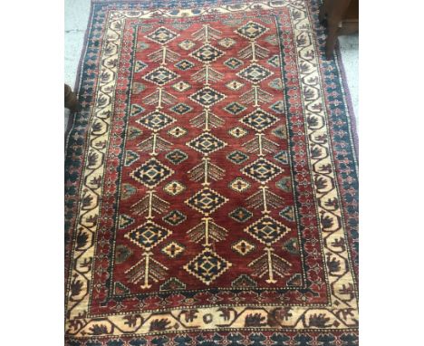 An Indian rug, the central panel set with repeating lozenge motifs on a red ground within a stepped red and blue stylised flo