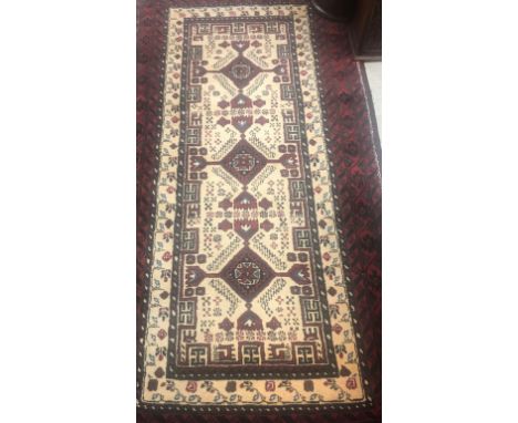 A Persian carpet, the central panel set with repeating diamond medallions on a cream ground within a red and black scrolling 