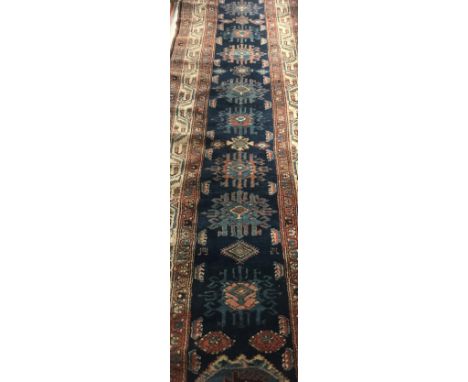 A Caucasian runner, the central panel set with repeating tarantula type motifs on a dark blue ground within a stepped cream, 