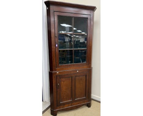 A 19th Century oak free standing corner cupboard, the moulded cornice over a glazed and barred single door enclosing a painte