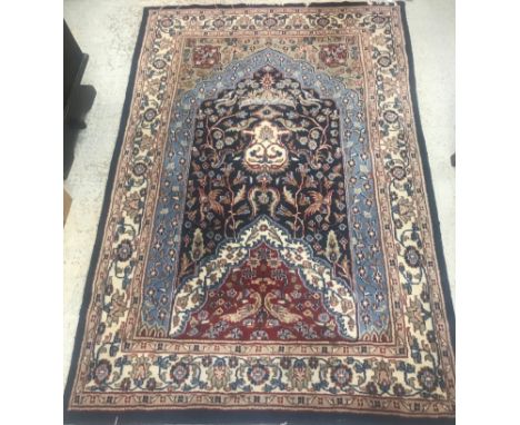 A Persian carpet of Mihrab style design, the central panel with foliate decoration on a blue, red and beige ground within a s