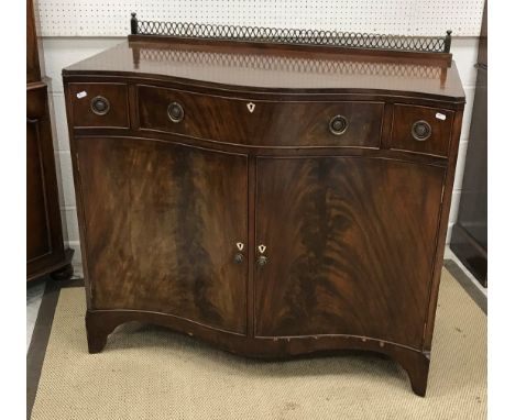 An Edwardian mahogany and cross banded serpentine fronted side cabinet with single long and two small drawers over two cupboa