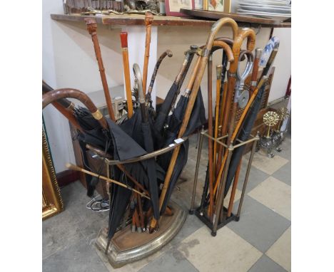 A cast iron stick stand and one other, and a large collection of walking sticks and umbrellas 