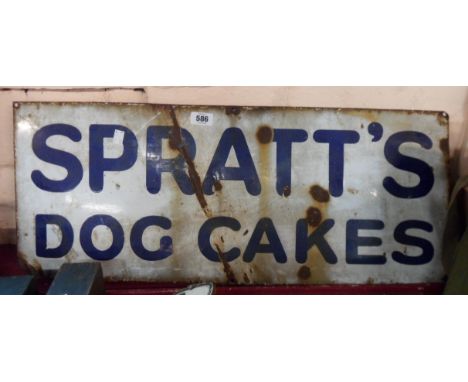 A vintage enamel sign advertising Spratt's Dog Cakes with blue lettering on a white ground - worn