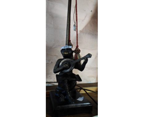 A cast resin table lamp depicting a monkey playing a lute with original shade