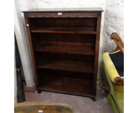 A 98cm Jaycee stained oak four shelf open bookcase with carved decoration, set on block feet