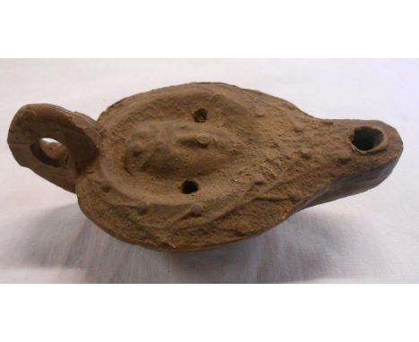 A Grand Tour Roman style pottery oil wick lamp with central mask within a foliate border - initials to base