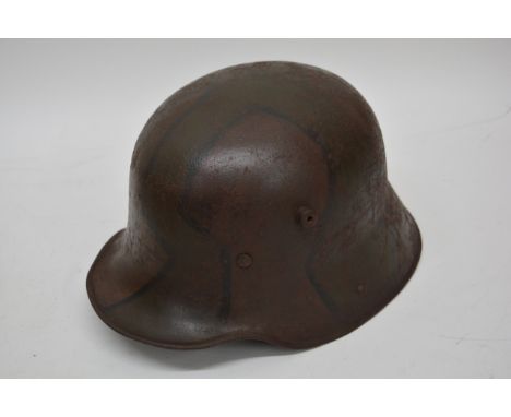 A Model M16 Stalhelm tin helmet with liner and faded camouflage paint.