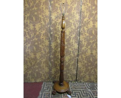 An oak standard lamp with carved column, raised on a disk shaped moulded platform and lions paw feet, (possibly partially con