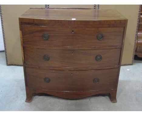 An early 19th century mahogany caddy top bow fronted bedroom chest of three long graduated drawers with shaped apron and swep