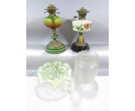 Two 19th century oil lamp bases, a pressed glass shade, a chimney and a Vaseline glass floral decorated shade. 