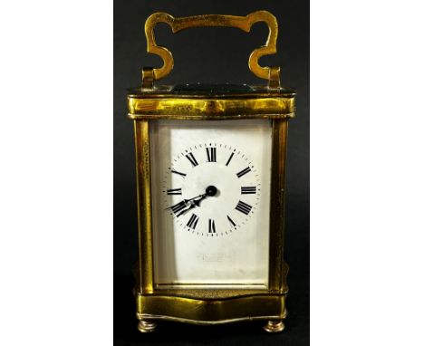 A brass carriage clock set within a shaped case with enamelled dial and eight day timepiece, currently running 