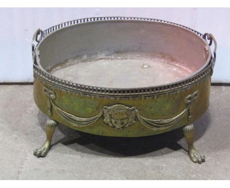 An oval brass planter with classical tied ribbon, swag and mask detail, removable liner and swept paw feet, 27 cm high x 50 c