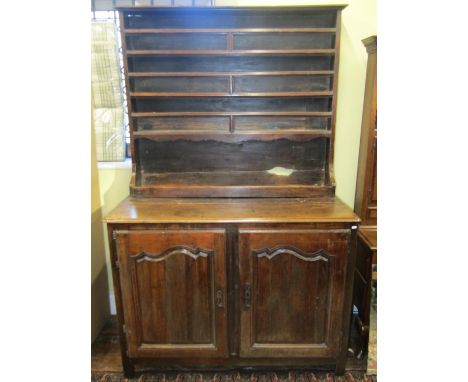 An antique French country made buffet in walnut and chestnut, enclosed by two shaped and panelled doors, with raised plate ra