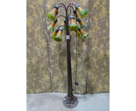 An ironwork lamp standard of full height fitted with twelve branches each fitted with a flower shaped shade in coloured glass