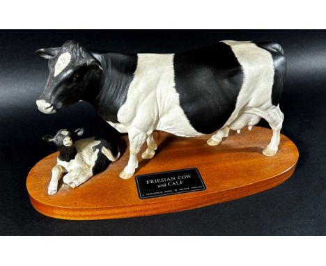A Beswick porcelain model of a Friesian cow &amp; calf on oval timber base