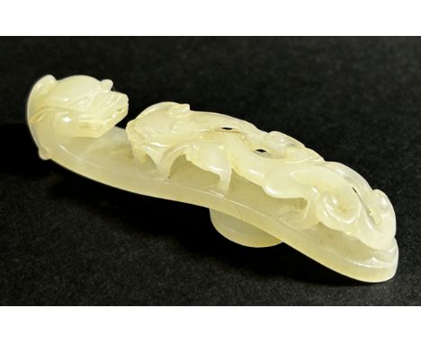 A pale Chinese jade belt hook, decorated with pierced dragon mounts, 8cm long, Qing dynasty or later. Provenance: Property of