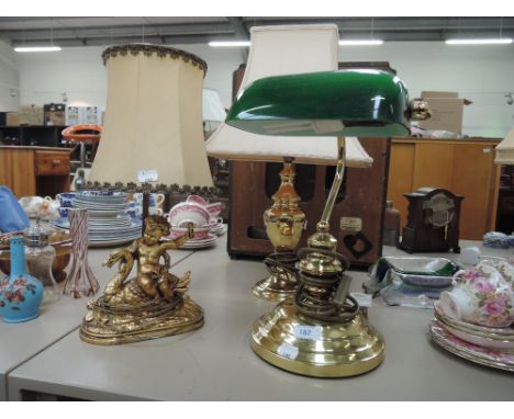 A desk lamp with brass stand and green glass shade, two table lamps with shades