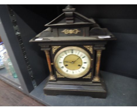 A late Victorian black marble mantel clock having architectural pediment and brass pillar decoration