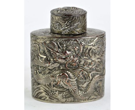 A Chinese white metal tea caddy and cover, decorated in high relief with dragons and waves, 12cm high, 19th or 20th CenturyCo