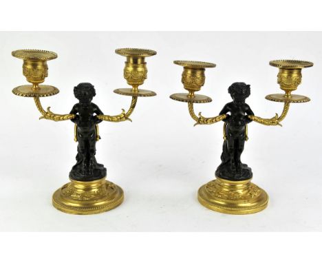 After Clodion, a pair patinated bronze and ormolu two light candelabra, cast as satyrs sitting on tree stumps H 19cm