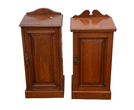 A matched pair of Edwardian walnut bedside cabinets, with differing crestings, above panelled doors with shelf within, on pli